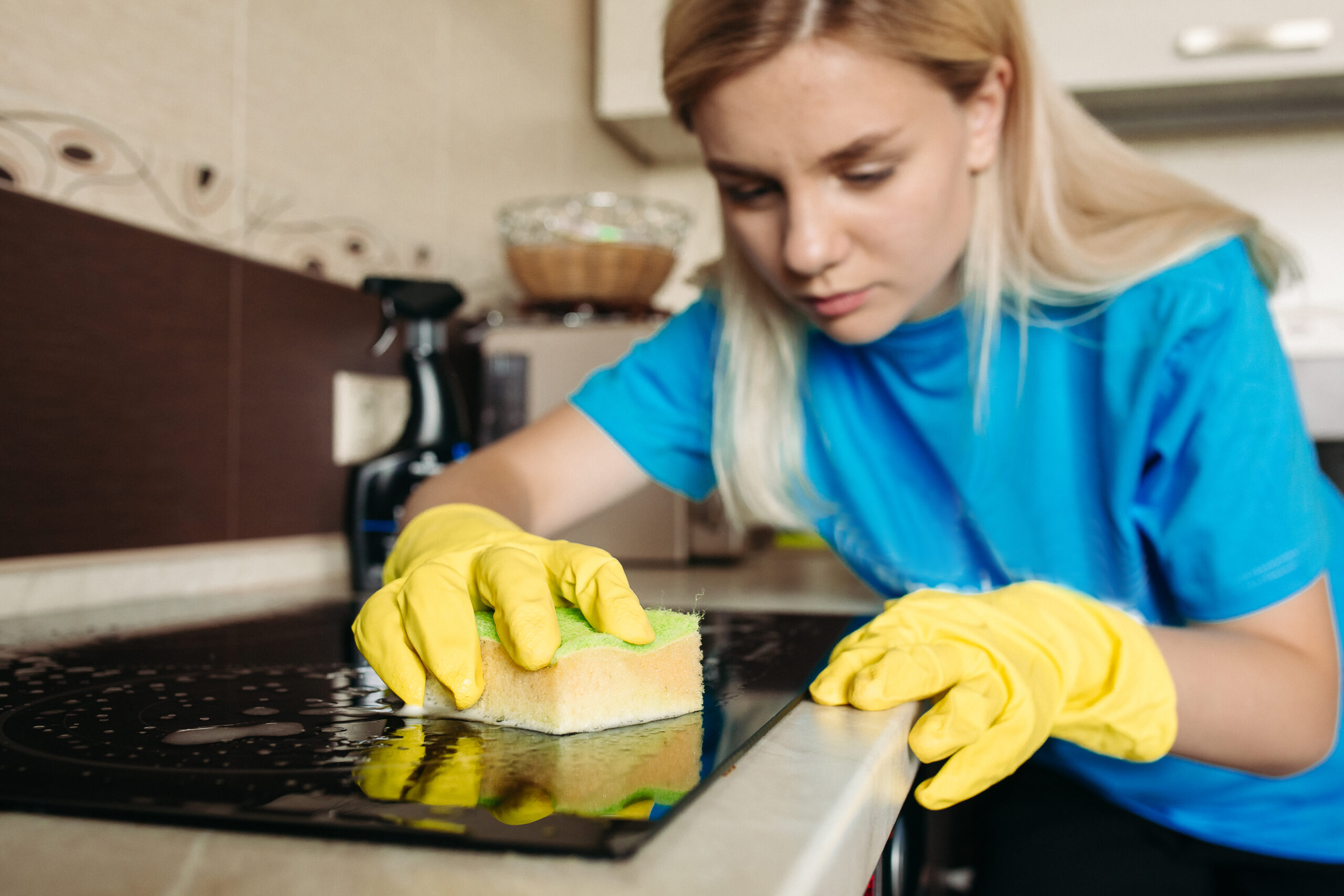 Woman, wearing in protective glove with rag, cleaning electric stove at home